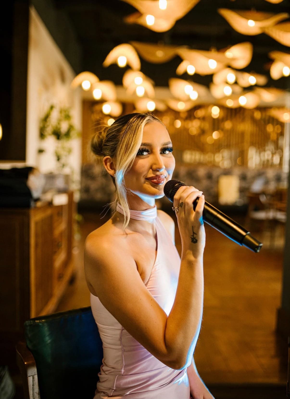 Dannii Murphy performing with a microphone under warm venue lighting